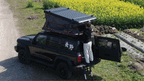 A overlander easily closing the Jiadrooe Titan T3021 aluminum hardshell tent for travel on a Toyota Tacoma rig.